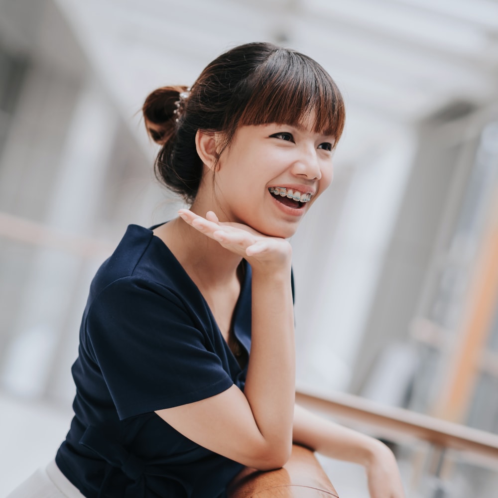 A girl is smiling and showing off her braces.